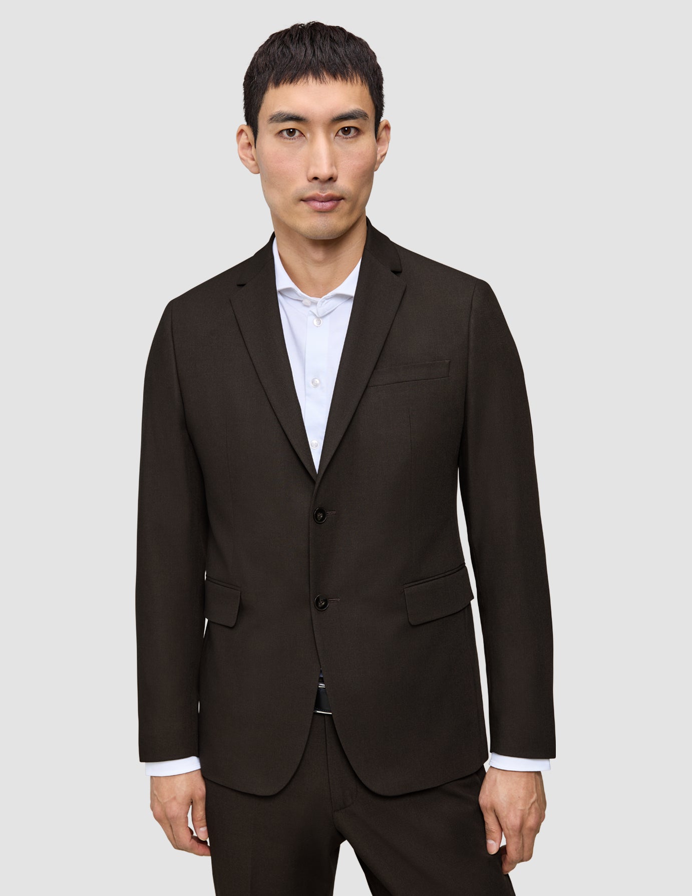 En man bär en mörkbrun Motion Blazer Regular Cognac över en vit skjorta med knappar.
