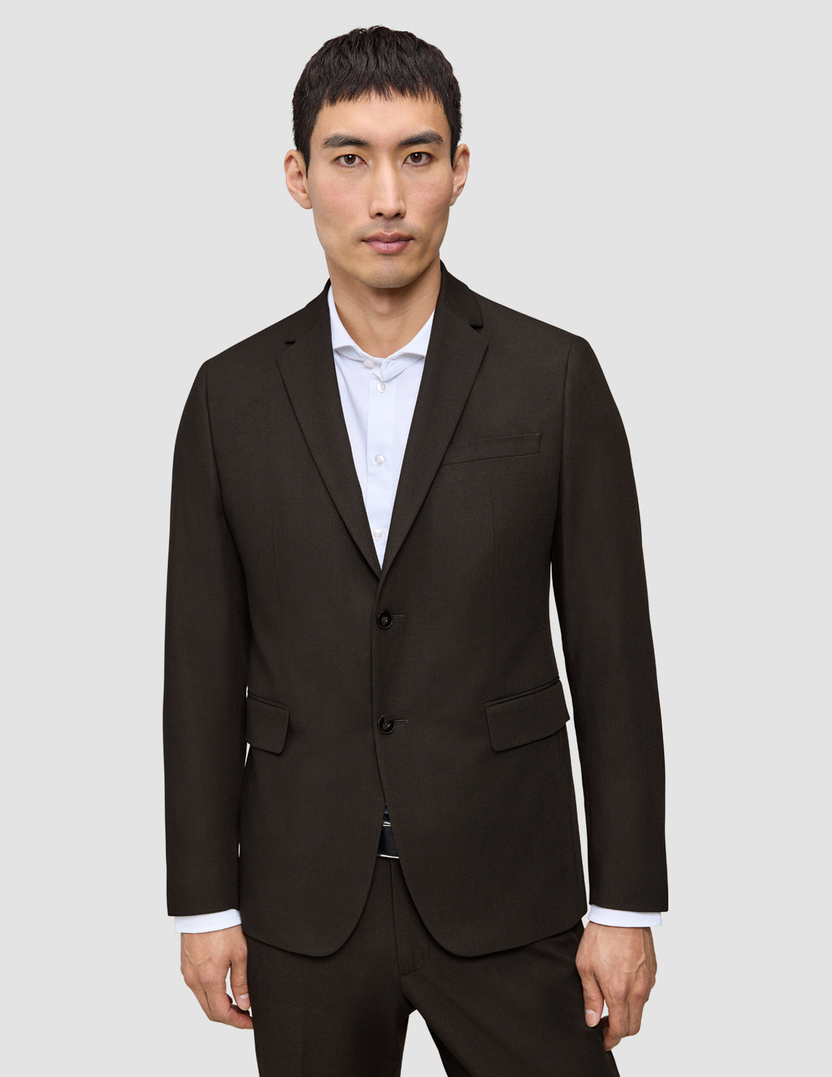 En man bär en mörkbrun Motion Blazer Regular Cognac över en vit skjorta med knappar.