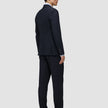 En man sedd bakifrån, klädd i en Motion Blazer Regular i färgen Midnight Blue, matchande byxor, en ljus skjorta och mörka loafers.