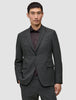 En man klädd i en Motion Blazer Regular i färgen Pepper Grey över en mörk skjorta med knappar.