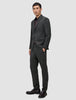 En man klädd i en Motion Blazer Regular i färgen Pepper Grey, en mörk skjorta med knappar, byxor och loafers, utformade för 360°-stretch.