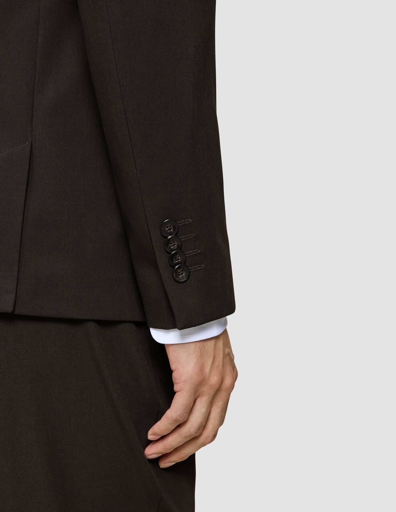 Närbild på en ärm från en Motion Blazer Slim Cognac med fyra knappar och en vit skjortmanschett som syns under.