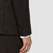 Närbild på en ärm från en Motion Blazer Slim Cognac med fyra knappar och en vit skjortmanschett som syns under.