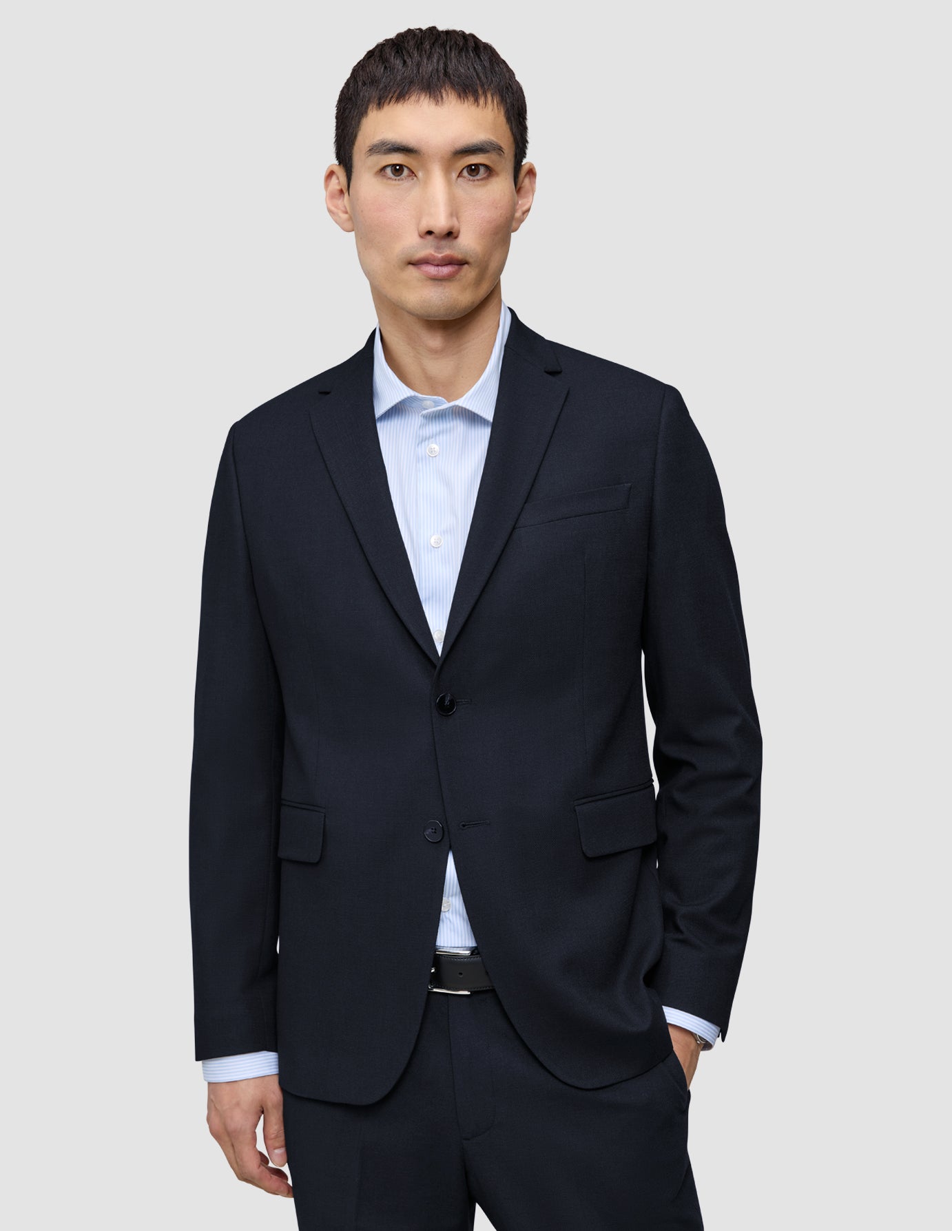En man bär en Motion Blazer Slim i färgen Midnight Blue över en ljusblå, randig skjorta med knappar.