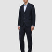 En man klädd i en Motion Blazer Slim i färgen Midnight Blue, en ljusblå skjorta med knappar och mörka loafers.