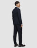 En person sedd bakifrån, klädd i en Motion Blazer Slim i färgen Midnight Blue, matchande byxor, en ljus skjorta och mörka loafers.