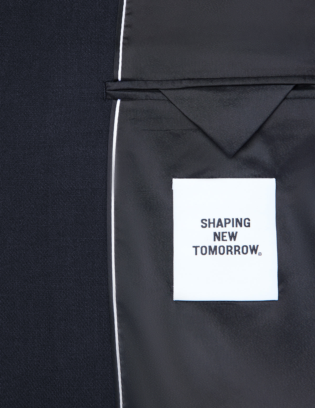 Insidan av en mörkblå Motion Blazer Slim Midnight Blue med en vit SHAPING NEW TOMORROW-etikett.