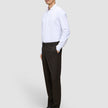En man klädd i en vit skjorta med knappar och byxor av modellen Motion Suit Pants Regular Cognac med 360°-stretch.