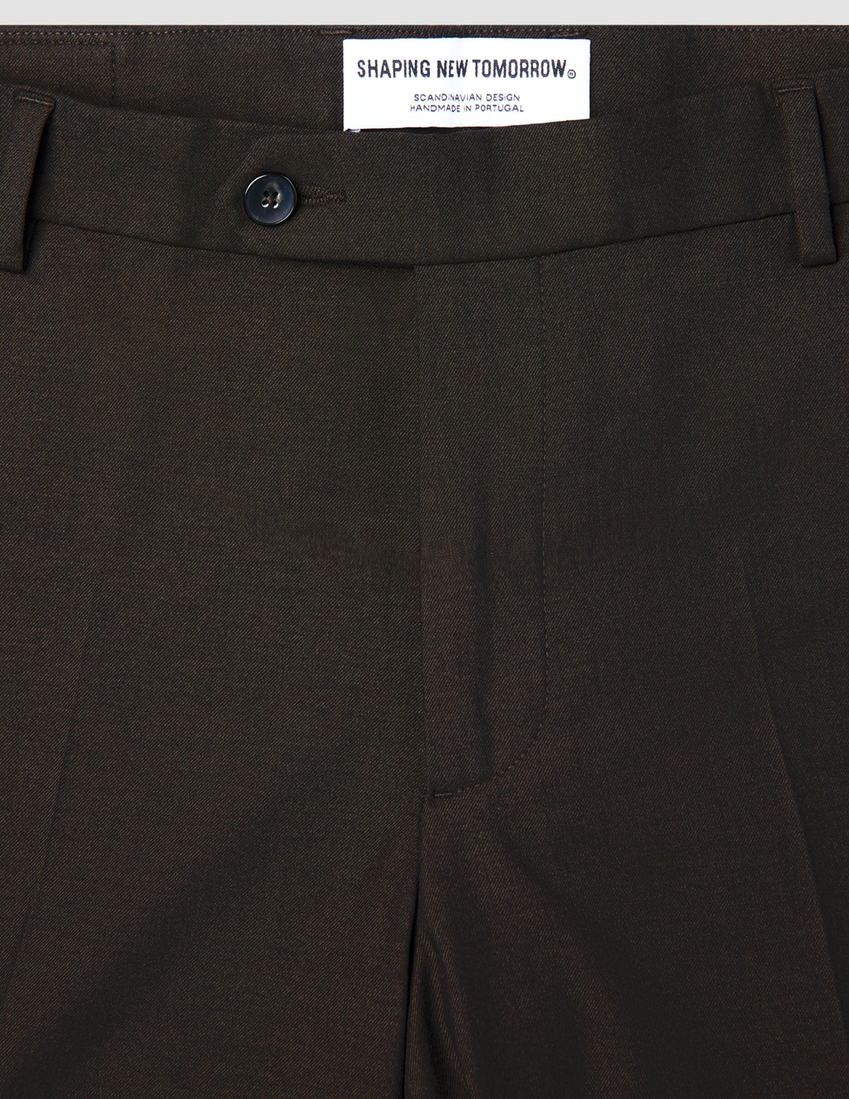 Mörkbruna Motion Suit-byxor i Regular-modell, färg: Cognac, med knäppning och en märkesetikett på insidan av midjebandet.