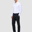 En man klädd i en vit skjorta, Motion Suit-byxor i storlek Regular i färgen Midnight Blue och mörka loafers.