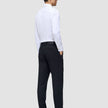 En man klädd i en vit skjorta och byxor av modellen Motion Suit Pants Regular Midnight Blue, sedd bakifrån.