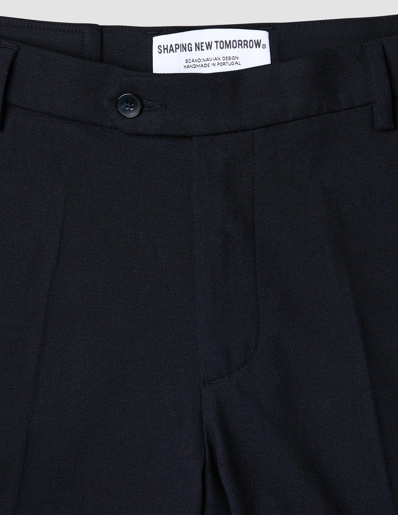 Närbild på marinblå Motion Suit-byxor i normal passform (Regular) i färgen Midnight Blue med 360°-stretch, knäppning och märkesetikett på insidan.