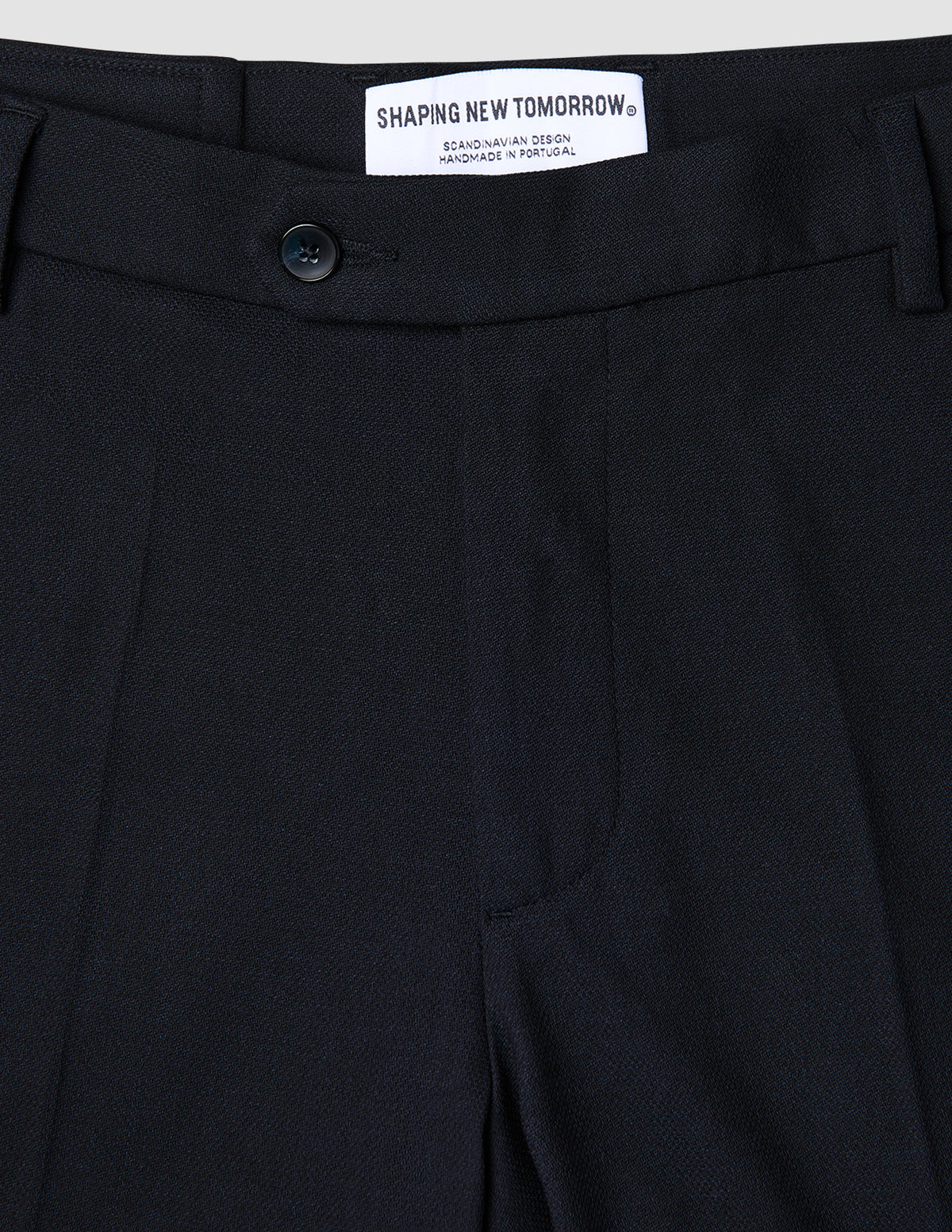 Närbild på marinblå Motion Suit-byxor i normal passform (Regular) i färgen Midnight Blue med 360°-stretch, knäppning och märkesetikett på insidan.