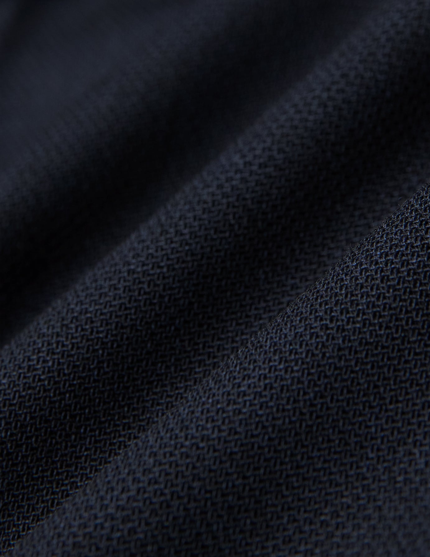 Närbild på vikta Motion Suit-byxor i storlek Regular, färgen Midnight Blue, med mörkblått strukturerat tyg och 360°-stretch.