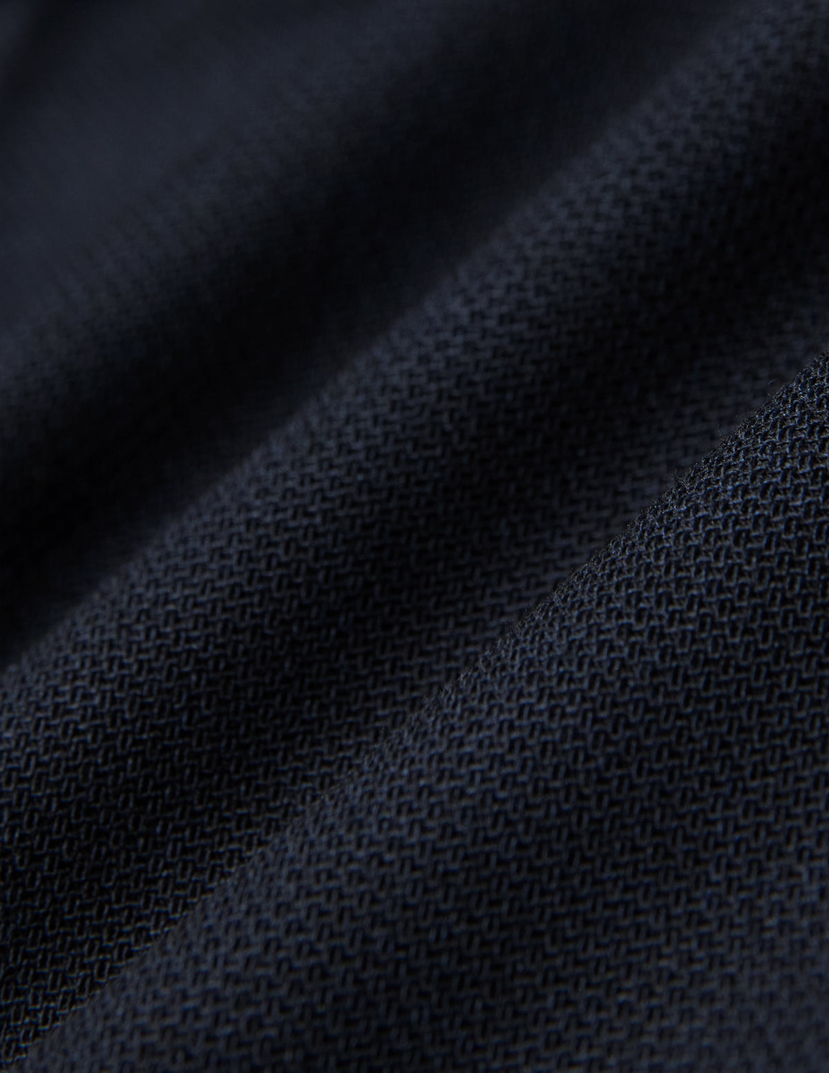 Närbild på vikta Motion Suit-byxor i storlek Regular, färgen Midnight Blue, med mörkblått strukturerat tyg och 360°-stretch.