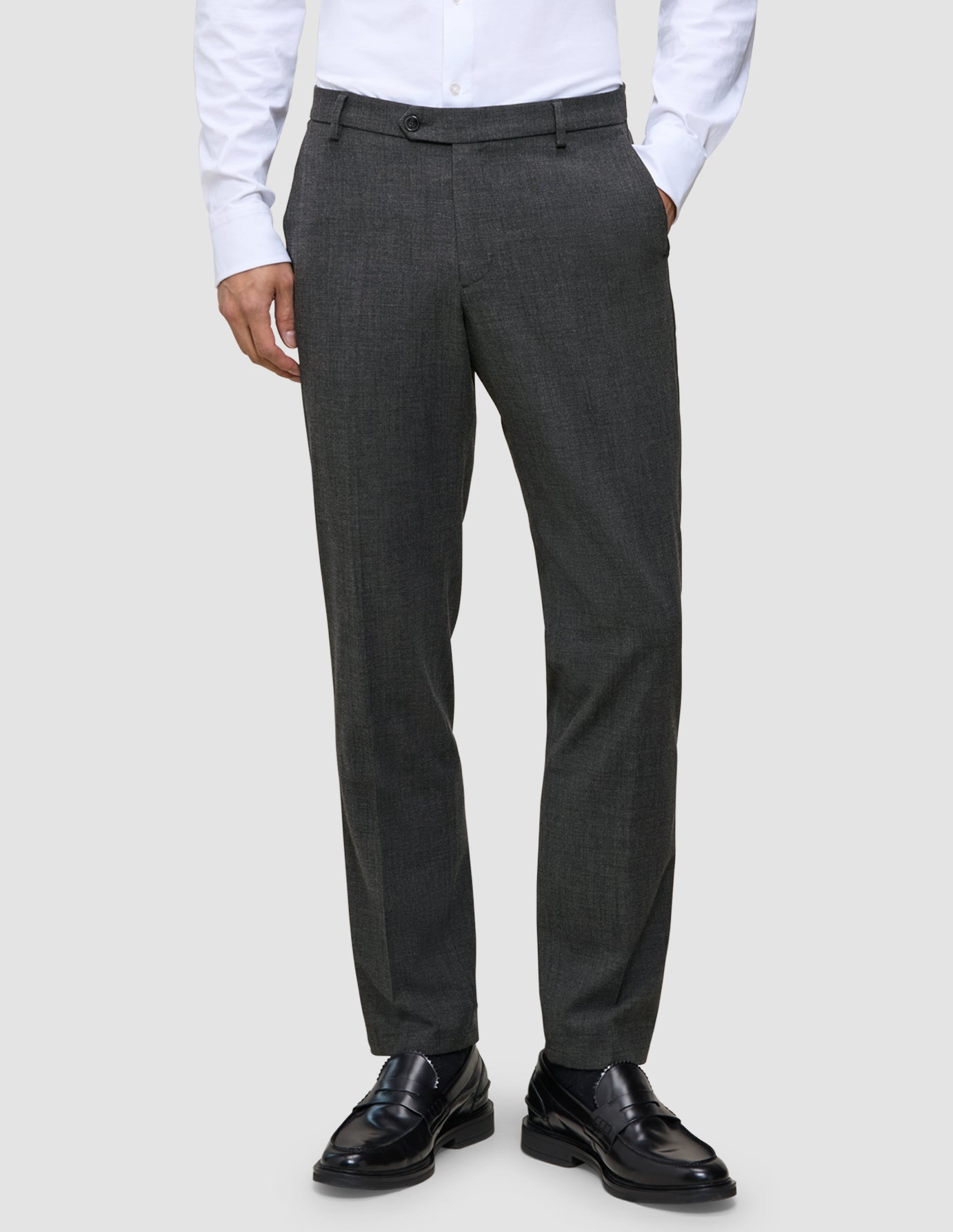 Motion Suit-byxor i Regular-passform, färg: Pepper Grey, kombinerade med en vit skjorta och svarta loafers.