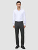 En man i en vit skjorta och byxor av modellen Motion Suit Pants Regular Pepper Grey, kombinerade med svarta loafers.