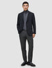 En man i svart kavaj och grå polotröja, klädd i Motion Suit Pants Regular Pepper Grey och svarta loafers.