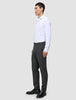 En man klädd i en vit skjorta, byxor av modellen Motion Suit Pants Regular Pepper Grey och svarta loafers i en ren skandinavisk design.