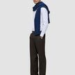 En man bär en vit skjorta med tunna ränder, en blå tröja och byxor av modellen Motion Suit Pants Relaxed Cognac med 360°-stretch.