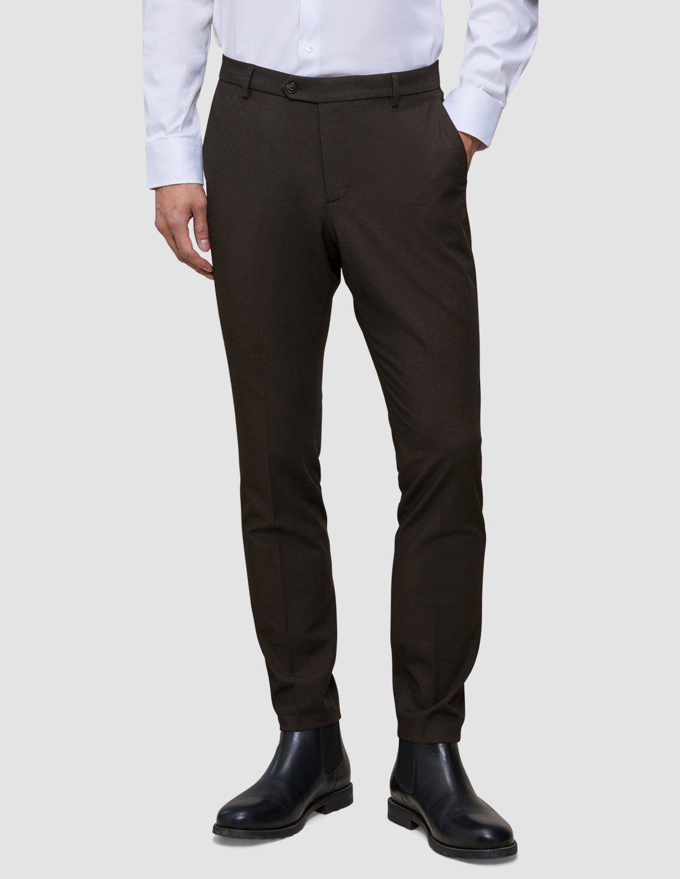 Mörkbruna Motion Suit-byxor i slim fit-modell, Slim Cognac, med 360°-stretch, vit skjorta med knappar och svarta Chelsea-kängor.