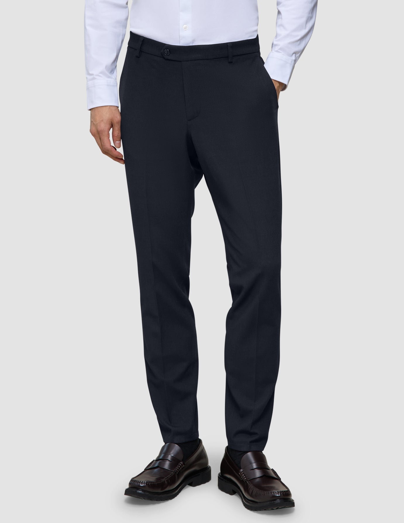Slim-fit Motion Suit-byxor i färgen Slim Midnight Blue med 360°-stretch, kombinerade med en vit skjorta och mörka loafers.