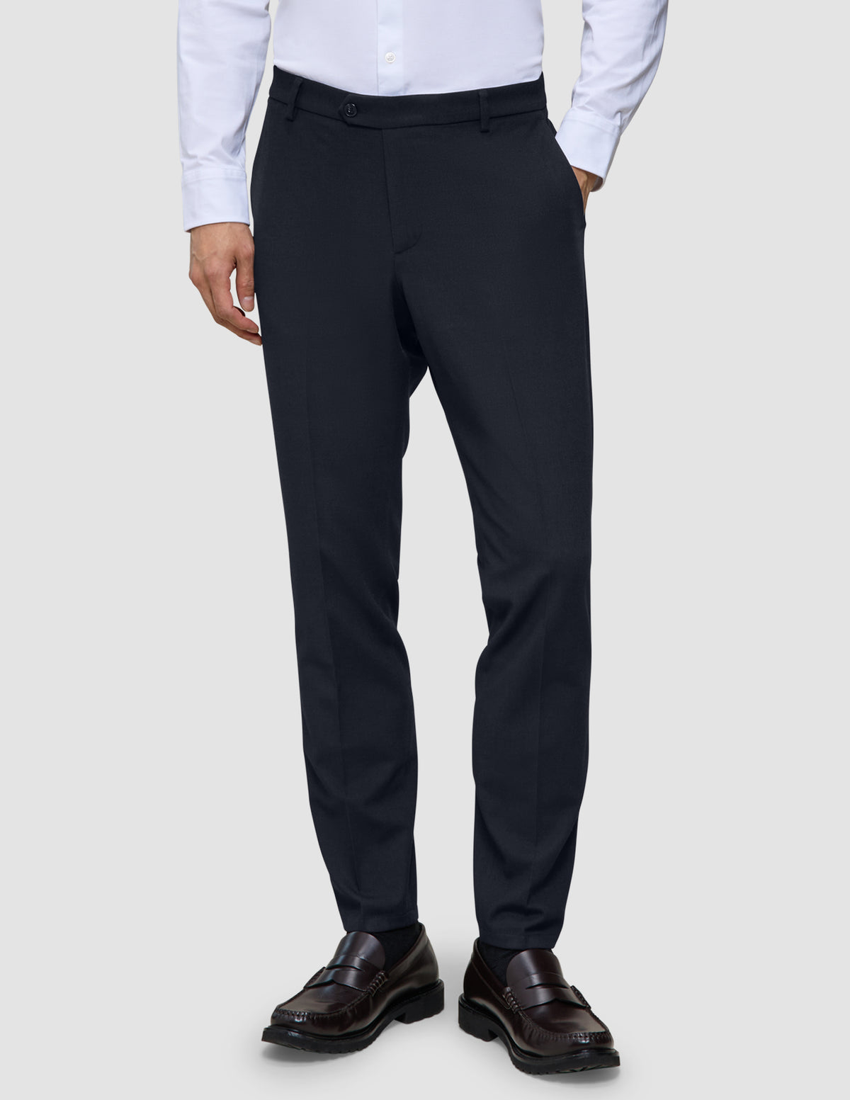 Slim-fit Motion Suit-byxor i färgen Slim Midnight Blue med 360°-stretch, kombinerade med en vit skjorta och mörka loafers.