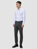 En man klädd i en vit skjorta med knappar, byxor av modellen Motion Suit Pants Slim Pepper Grey och svarta kostymskor.