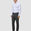 En man klädd i en vit skjorta med knappar, byxor av modellen Motion Suit Pants Slim Pepper Grey och svarta kostymskor.