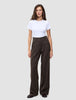 En person bär en vit t-shirt och byxorna Serene Pants Wide Walnut Herringbone: bruna byxor med hög midja och vida ben.