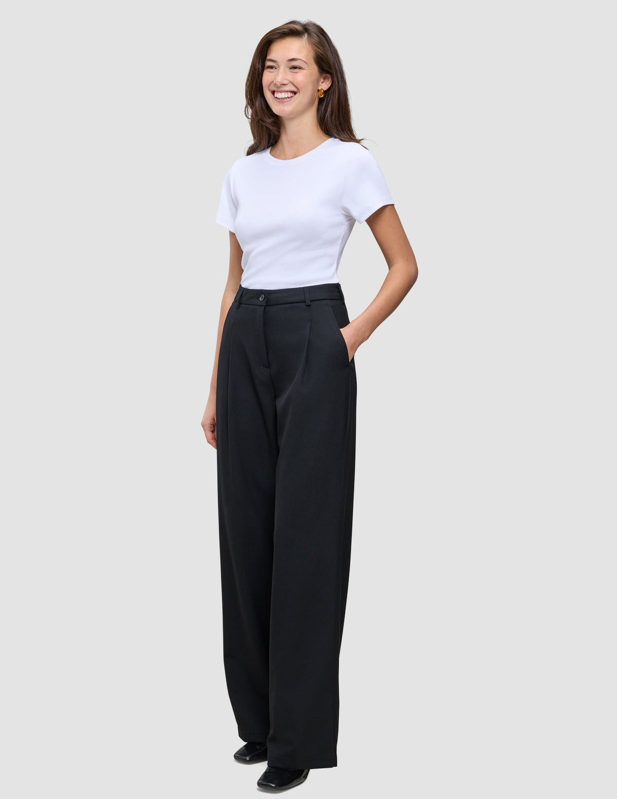 En kvinna klädd i en vit t-shirt och svarta Serene Pants Wide Black med hög midja.