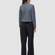 En person sedd bakifrån, klädd i en grå kavaj och svarta Serene Pants Wide Black med hög midja.