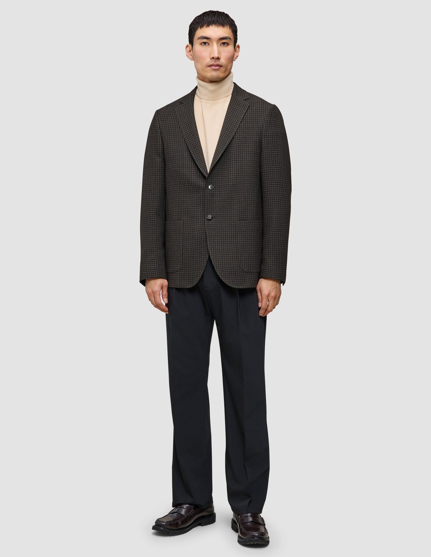 Stilen med stickat och kavaj: en mönstrad ullkavaj, en beige merinotröja med rund hals, mörka byxor och loafers.