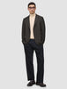 En person som bär en mörkbrun rutig Timeless Wool Blazer Slim över en beige polotröja och mörka byxor.