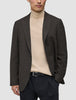 En person som bär en mörkbrun rutig Timeless Wool Blazer Slim över en beige polotröja och svarta byxor.