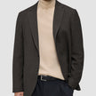 En person som bär en mörkbrun rutig Timeless Wool Blazer Slim över en beige polotröja och svarta byxor.