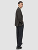 En person klädd i en mörkbrun rutig Timeless Wool Blazer Slim, en beige polotröja och mörka byxor.