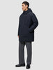 En person klädd i en vind- och vattentät svart Utility Jacket Black med dragkedja framtill och grå byxor.
