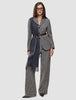 En person klädd i en grå blazer med fiskbensmönster och byxor av modellen Women Ashryn Pants Wide Domino Herringbone, med ett brunt bälte och en lång halsduk.