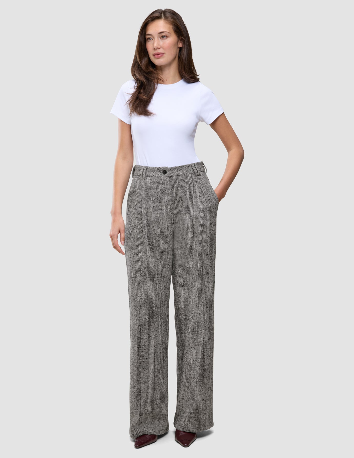 En kvinna bär en vit t-shirt och byxorna Women Ashryn Pants Wide Domino Herringbone i en skandinavisk stil.