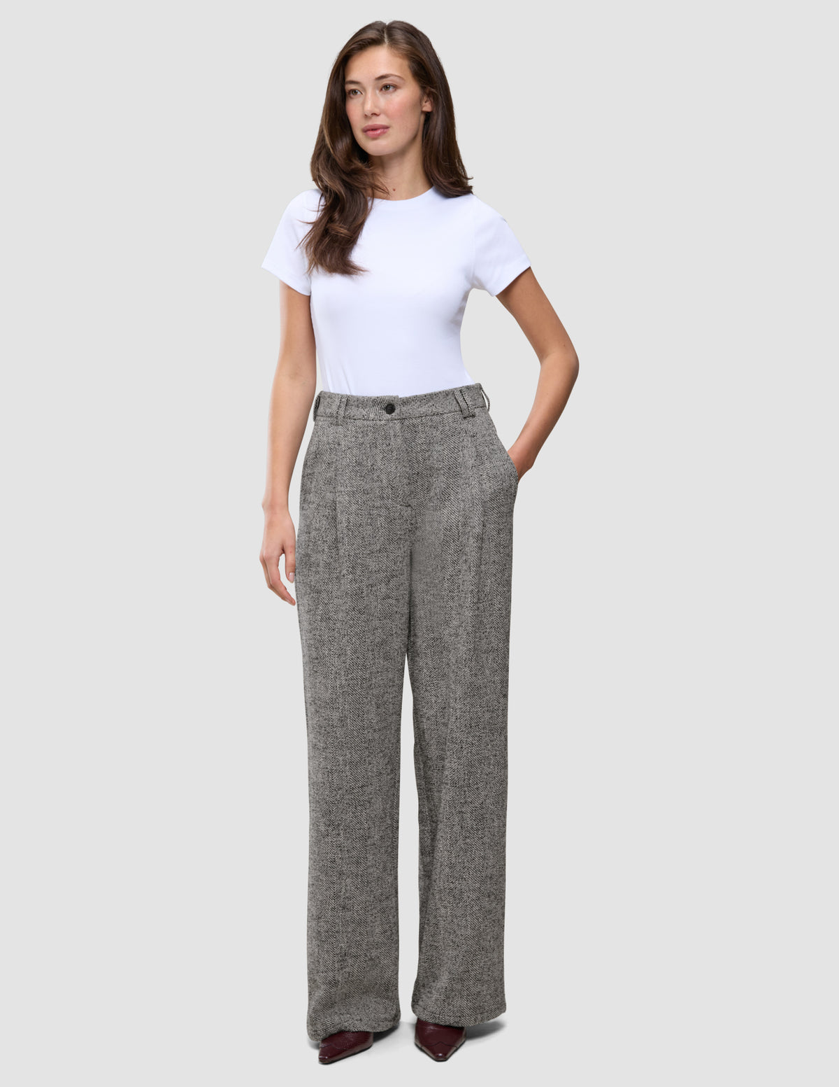 En kvinna bär en vit t-shirt och byxorna Women Ashryn Pants Wide Domino Herringbone i en skandinavisk stil.