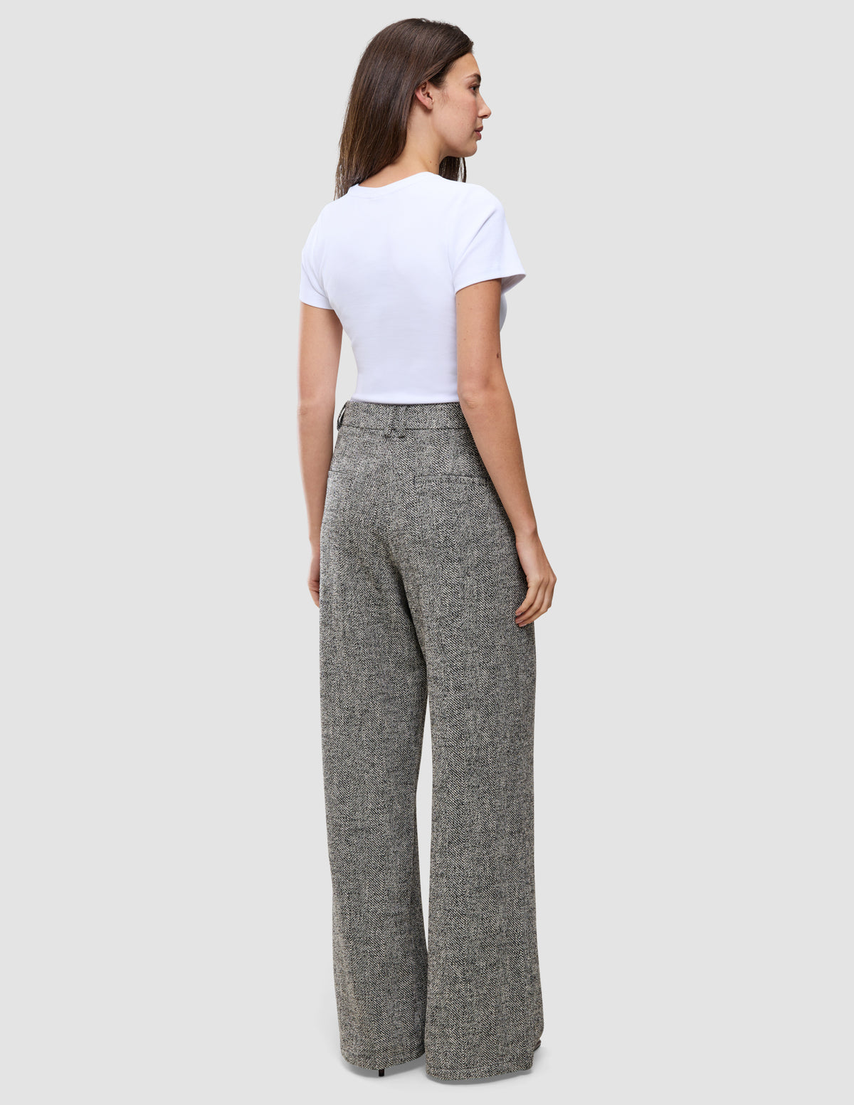 En person sedd bakifrån, klädd i en vit t-shirt och gråmönstrade Women Ashryn Pants Wide Domino Herringbone.