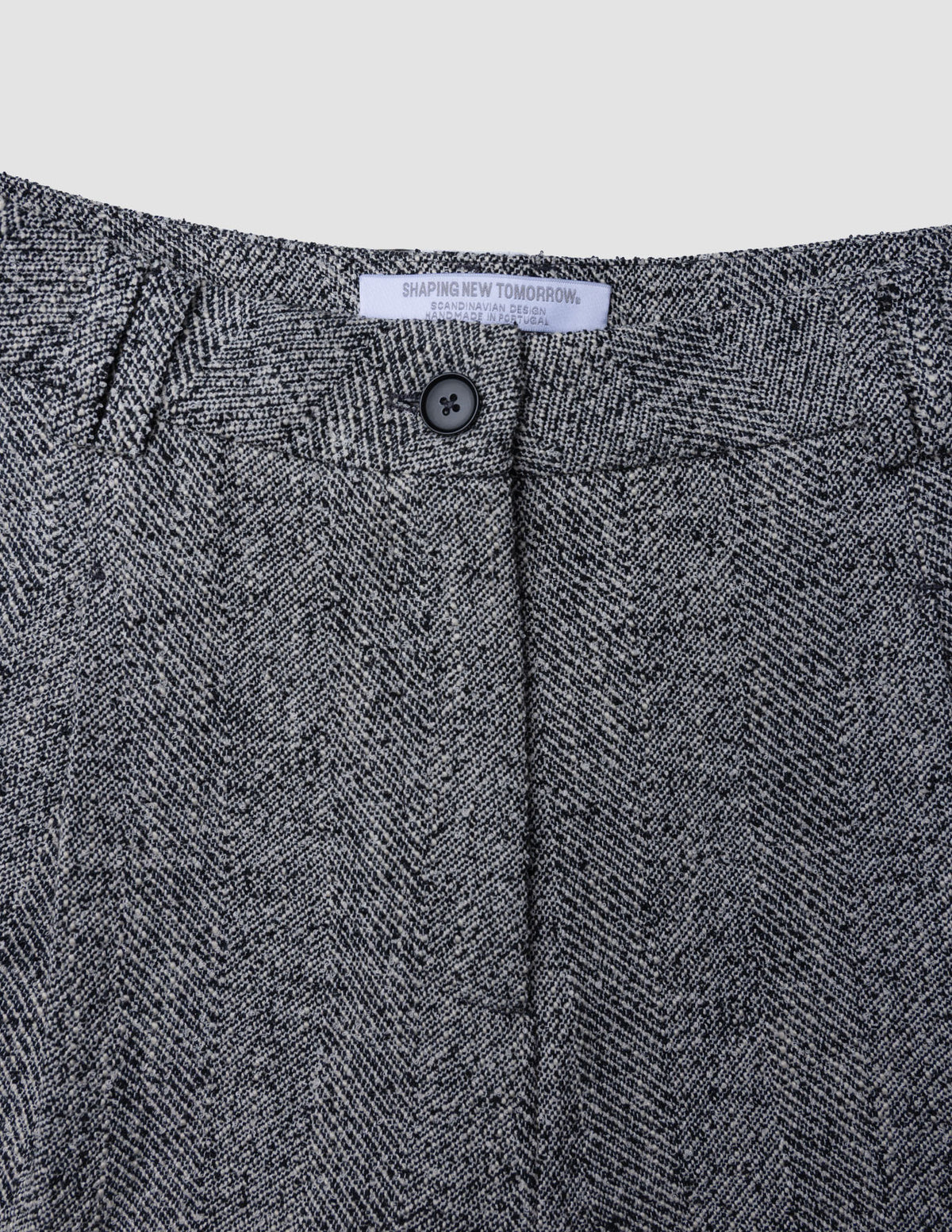 Närbild på Ashryn-byxor för damer, modell Wide Domino Herringbone, med hög midja och ett grått och svart fiskbensmönster.