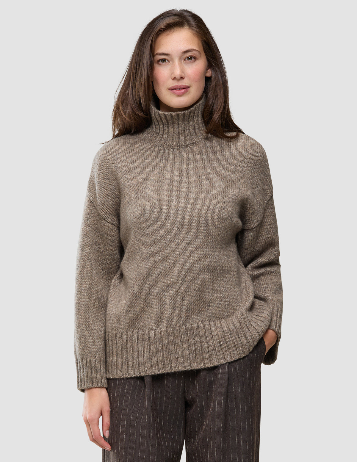 En kvinna klädd i en tjock, mjuk ulltröja med hög hals i färgen taupe melange från kollektionen Women.