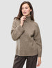 En kvinna klädd i en tjock, mjuk ullstickad turtleneck-tröja i färgen taupe melange från kollektionen Women.
