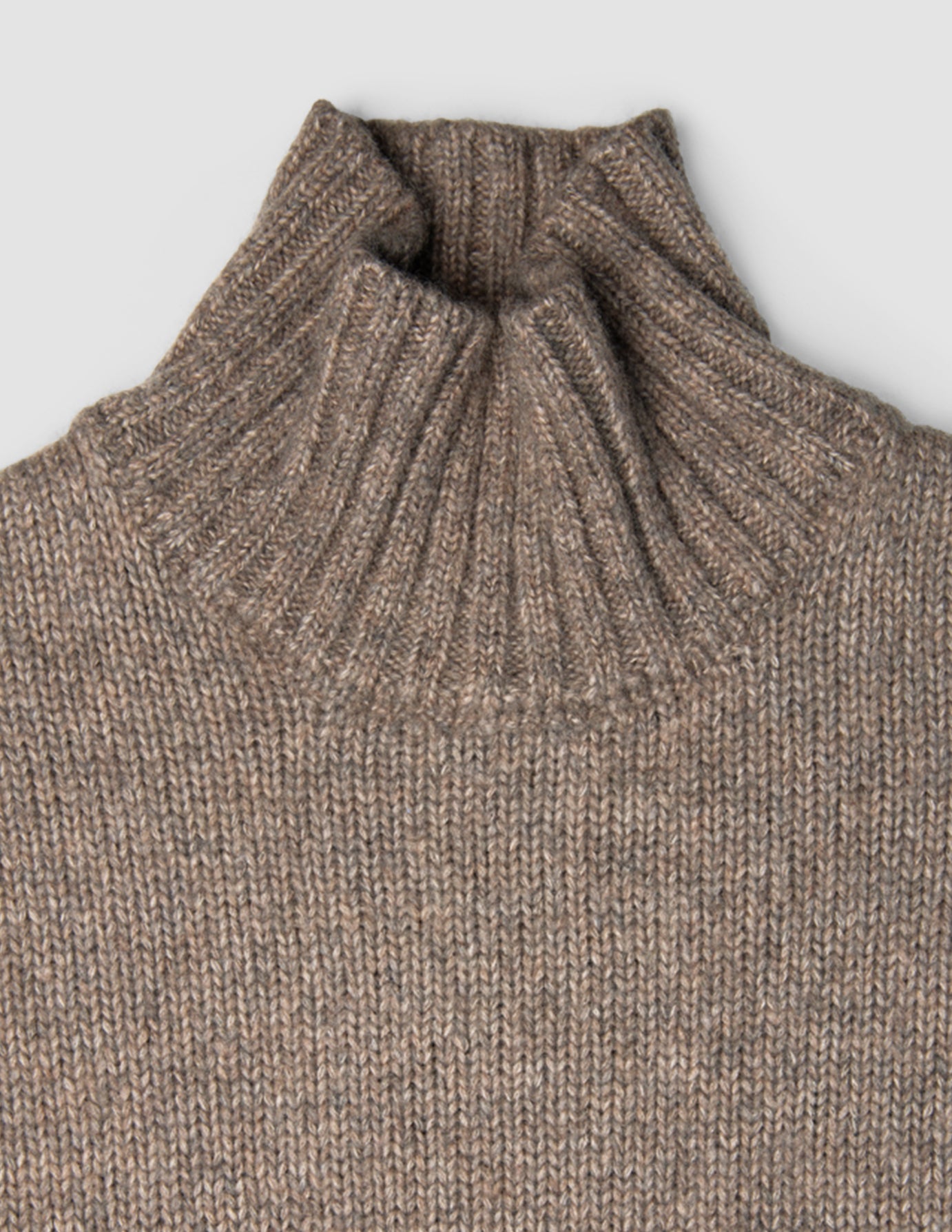 Dammåttig, tjock och mjuk ulltröja med hög hals i taupe-melange och ribbad struktur.