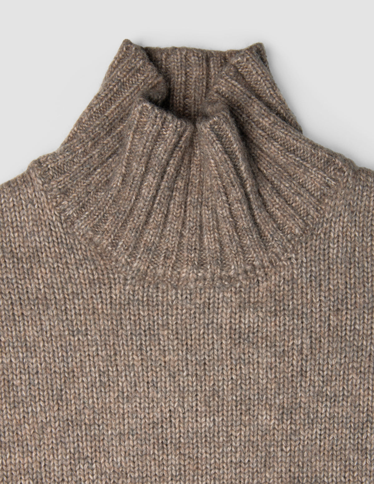 Dammåttig, tjock och mjuk ulltröja med hög hals i taupe-melange och ribbad struktur.