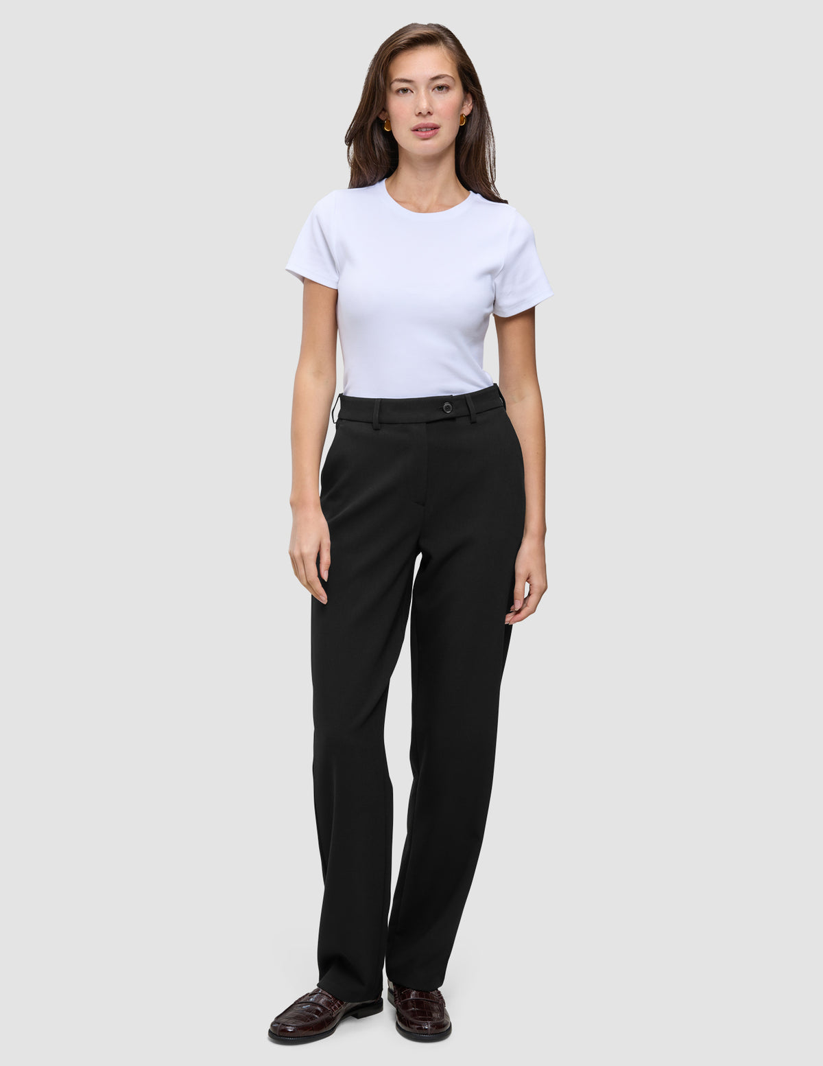En person som bär en vit t-shirt och byxor av modellen Women GO2 Pants Straight Black med raka ben.