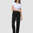 En kvinna klädd i en vit t-shirt, Women GO2 Pants Straight Black och mörka loafers i en ren skandinavisk design.