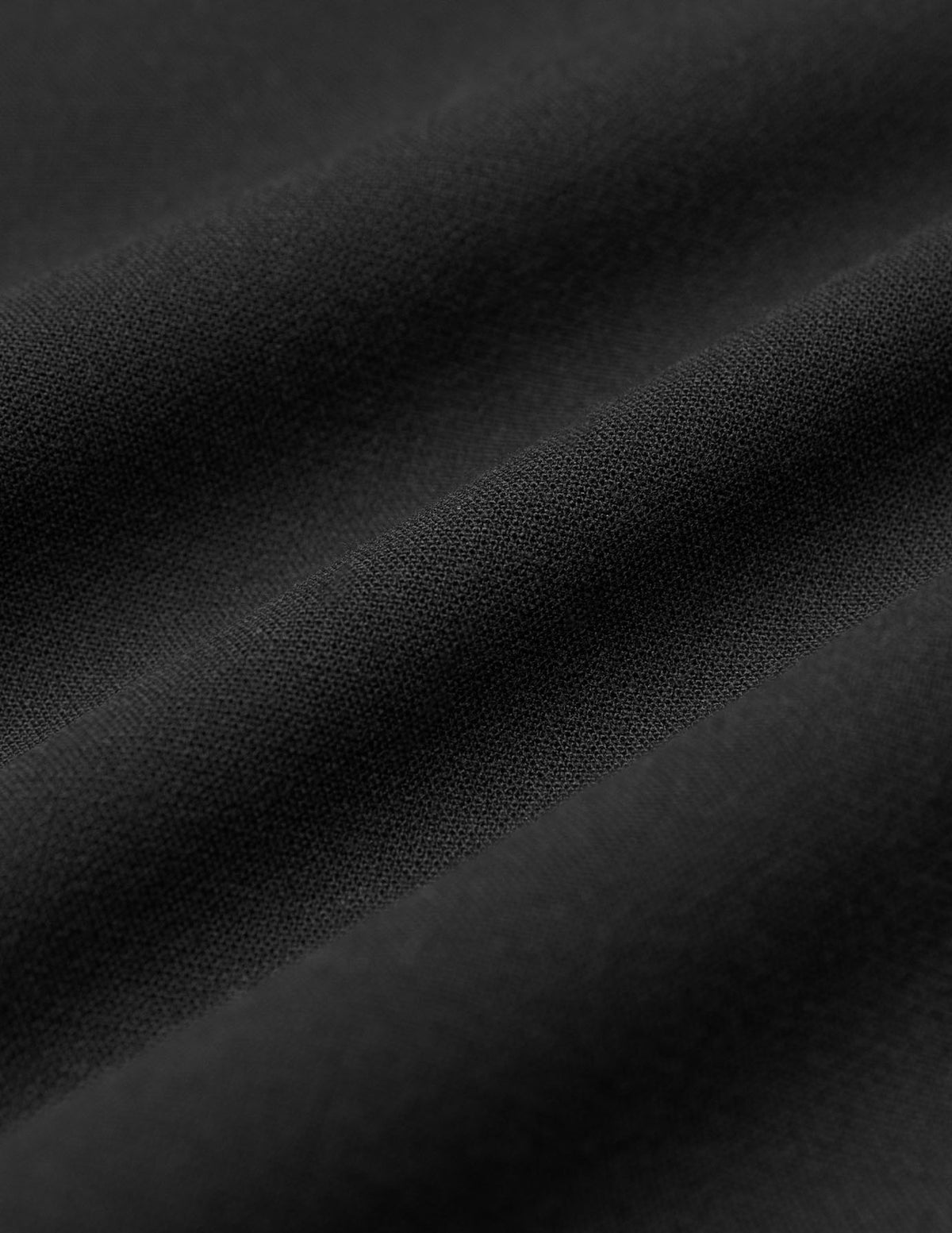 Närbild på svarta GO2-byxor i rak modell (Black) där tygveck syns tydligt.
